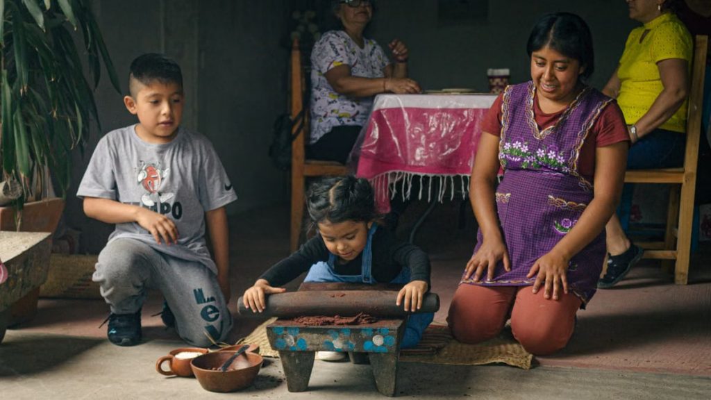 Children and adults enjoying traditional cooking indoors, showcasing cultural heritage.